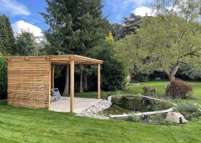 Slatted cedar wood pergola adjacent to newly installed pond