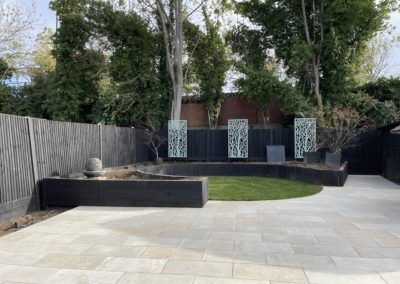 Porcelain paving and circular raised beds.Decorative screens